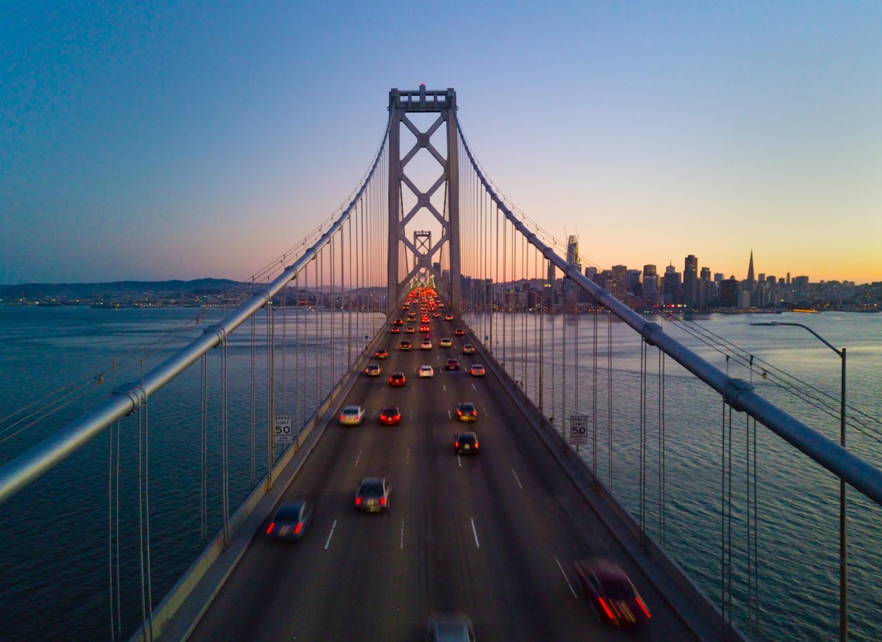 Aerial view of Bay Bridge leading into San Francisco skyline during twilight.