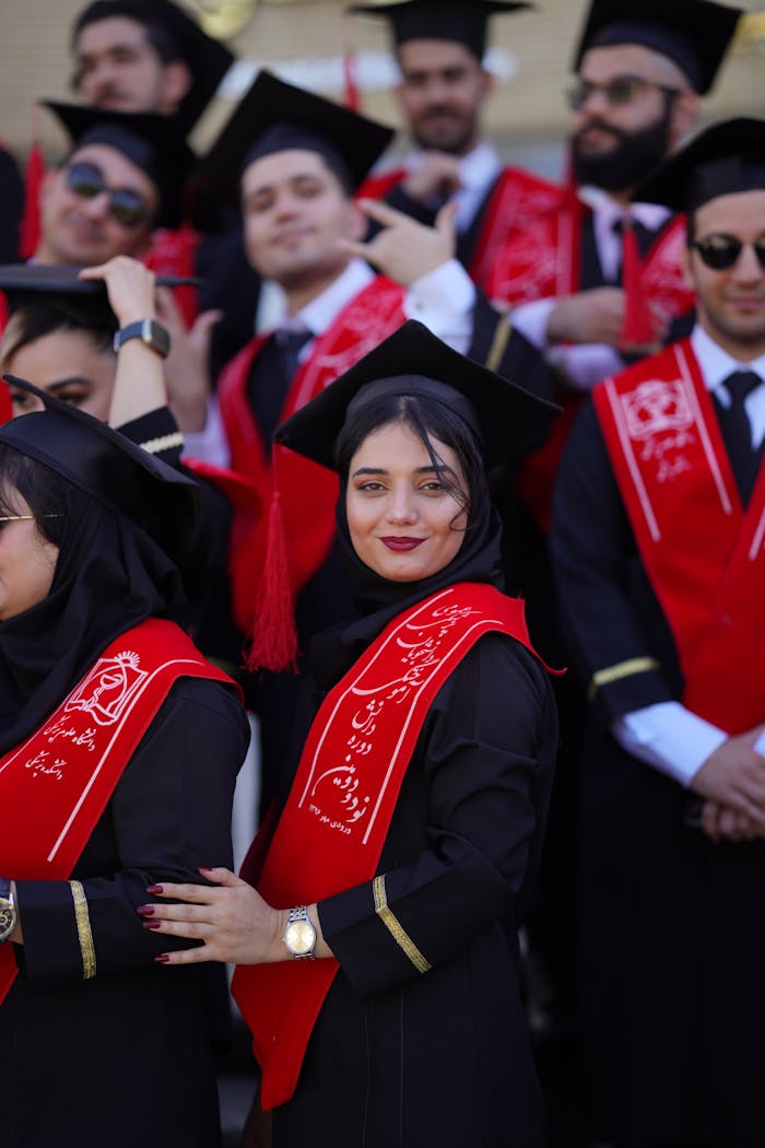 Group of graduates in Iran celebrating their graduation with caps and red sashes.